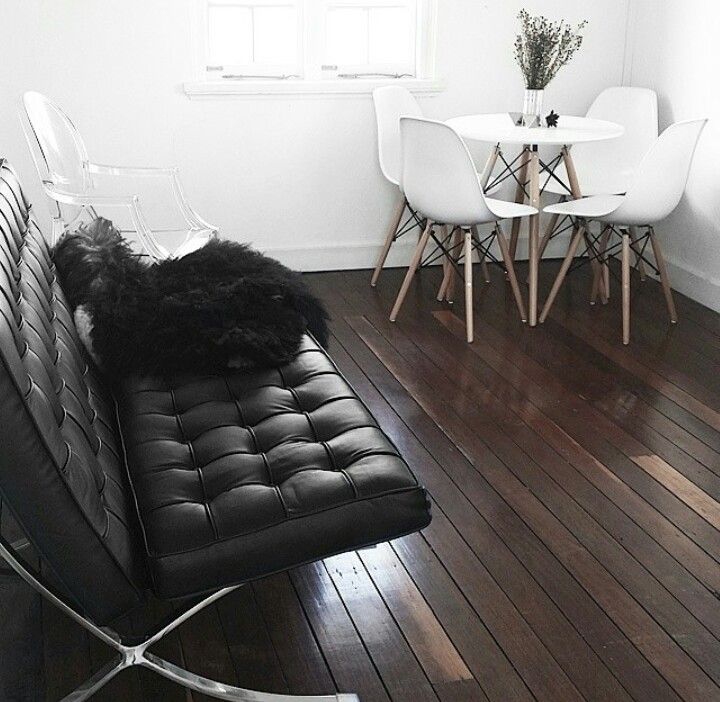 a black leather couch sitting on top of a hard wood floor next to a white table