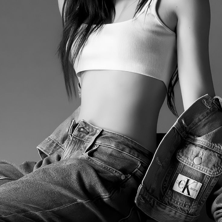 a black and white photo of a woman in jeans with her hands on her hips