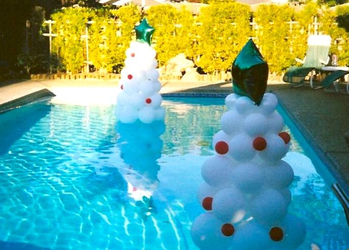 two inflatable christmas trees sitting next to a swimming pool