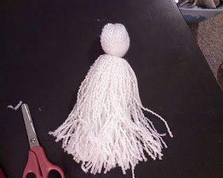 a pair of scissors sitting on top of a table next to a white tassel