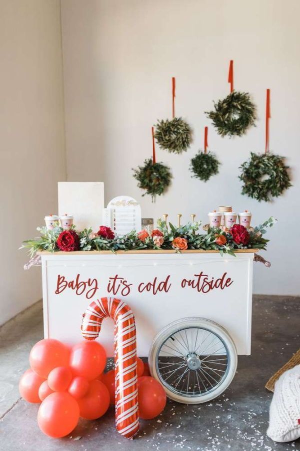 a baby it's cold outside cart with balloons and wreaths on the wall