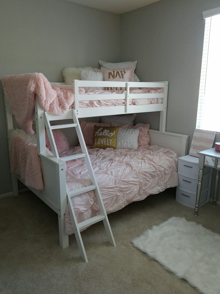 a white bunk bed sitting in a bedroom next to a desk and chair with a pillow on top of it