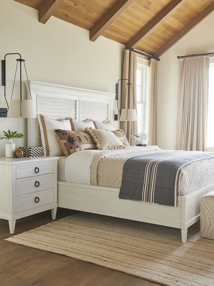 a white bed sitting in a bedroom on top of a wooden floor next to a window