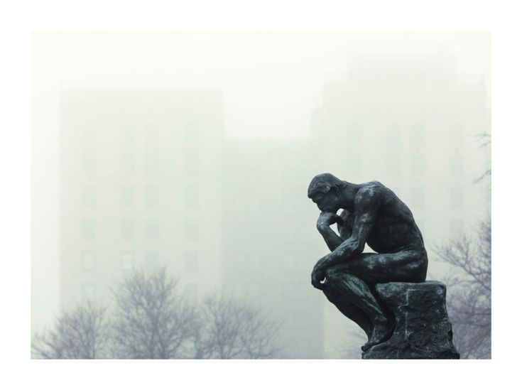 a statue of a man sitting on top of a rock