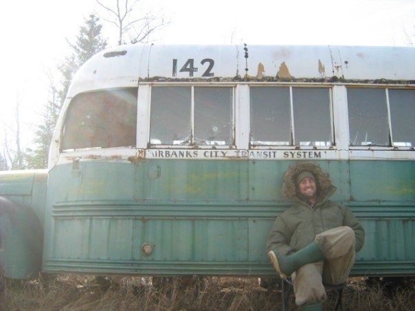 a person sitting on the ground in front of an old bus that says happiness is only real when shared