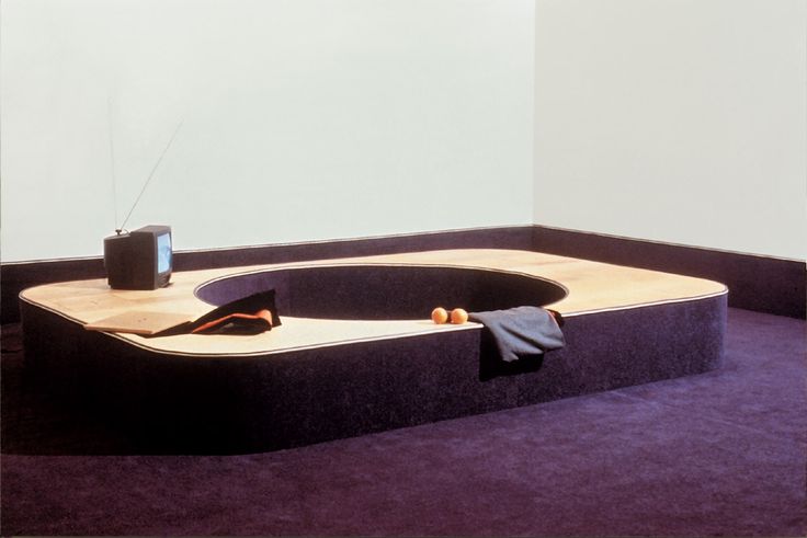 an oval shaped bench with a television on it in a room filled with purple carpet