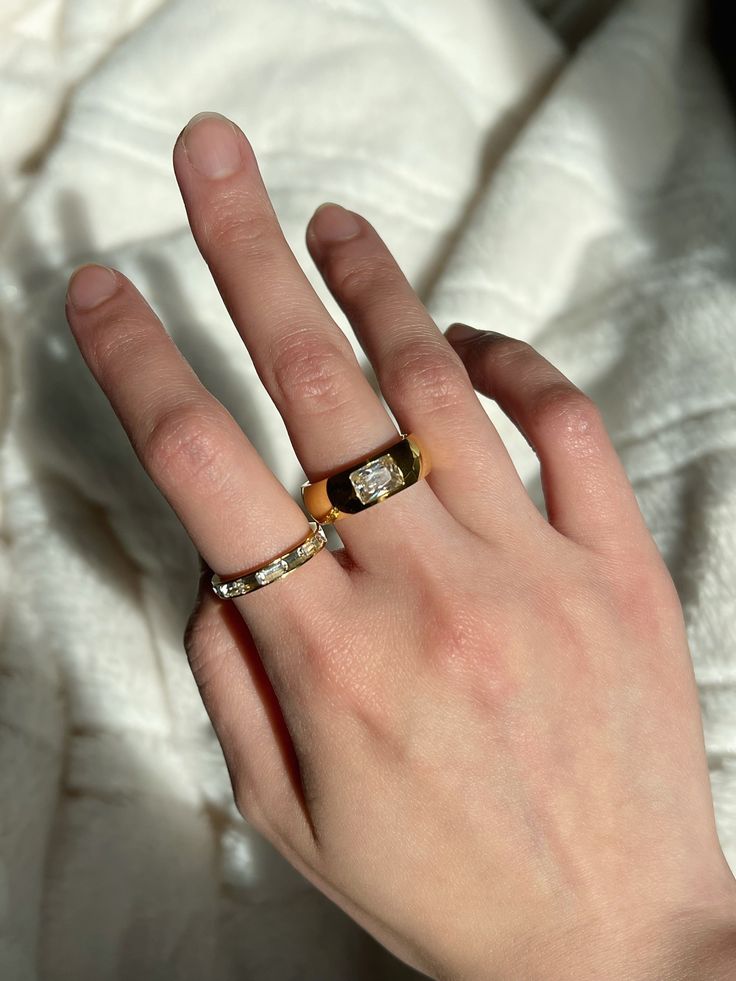 I'd like to call this Zoe Ring the do-it-all ring. It's minimal but it's definitely a statement ring. A thick gold band topped with a square cut CZ stone. Dipped in 18K Gold; Stainless Steel Band Width: 7mm Available in sizes: 6,7,8 Modern Everyday Ring With Rectangular Stone, Classic Open Crystal Ring For Everyday, Modern Everyday Rings With Rectangular Stone, Modern Thick Band Diamond Ring As Gift, Modern Gold Ring With Rectangular Stone, Minimalist Gold Ring With Rectangular Stone, Classic Everyday Yellow Gold Crystal Ring, Everyday Classic Yellow Gold Crystal Ring, Square Cut Single Diamond Ring Gift