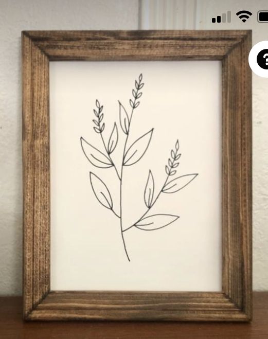 a wooden frame with a drawing of a plant in it on top of a table