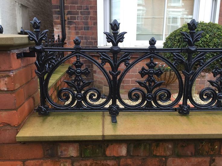 a black iron fence sitting on the side of a brick wall next to a window