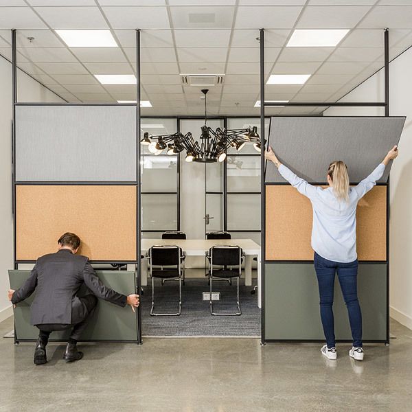 two people are sitting in an office cubicle with their arms up and hands on the wall