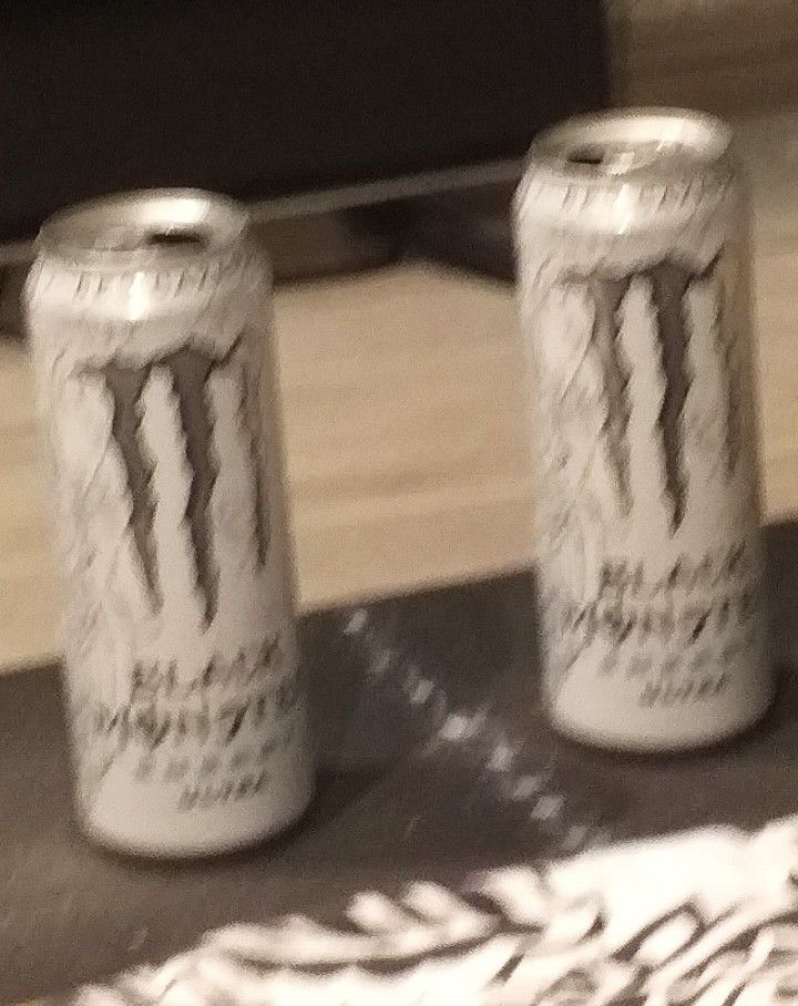 two cans of monster energy drink sitting on a table