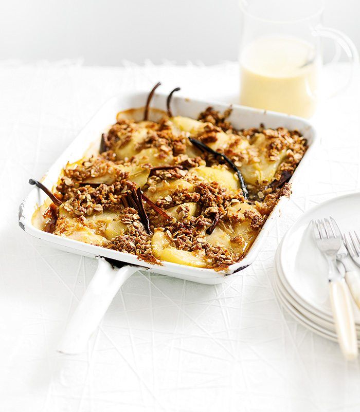 a casserole dish filled with bananas and granola next to a glass of milk