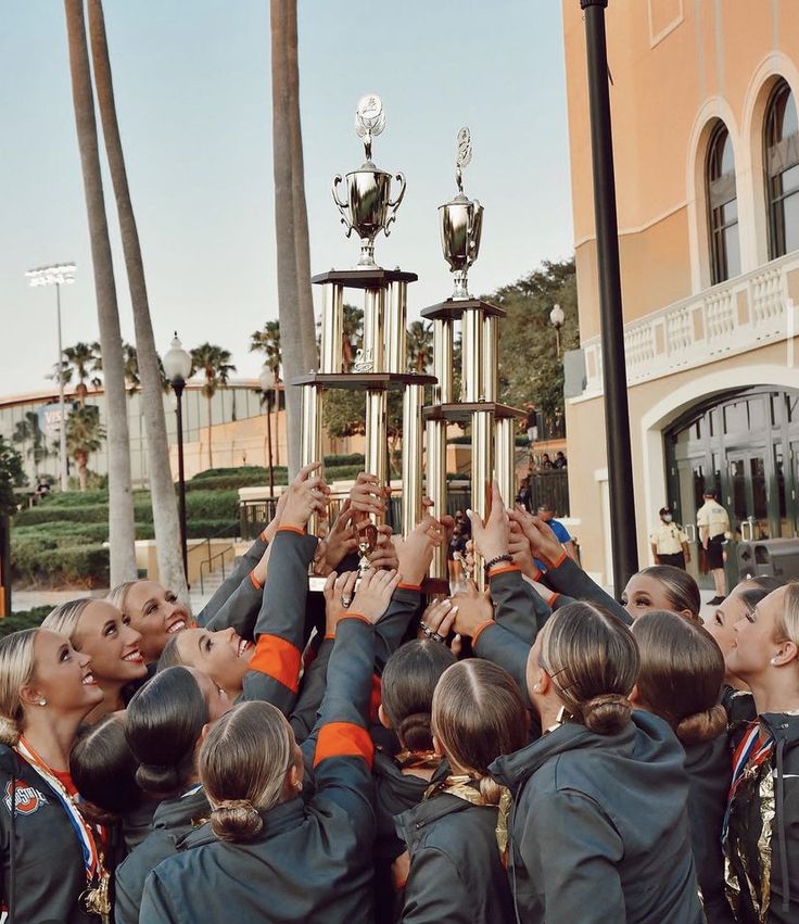 a group of young women standing next to each other in front of a trophy