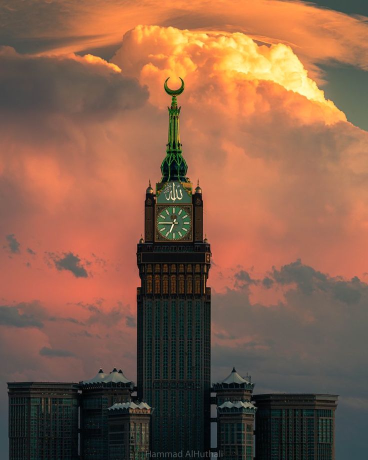 a large clock tower towering over a city under a pink sky with clouds in the background