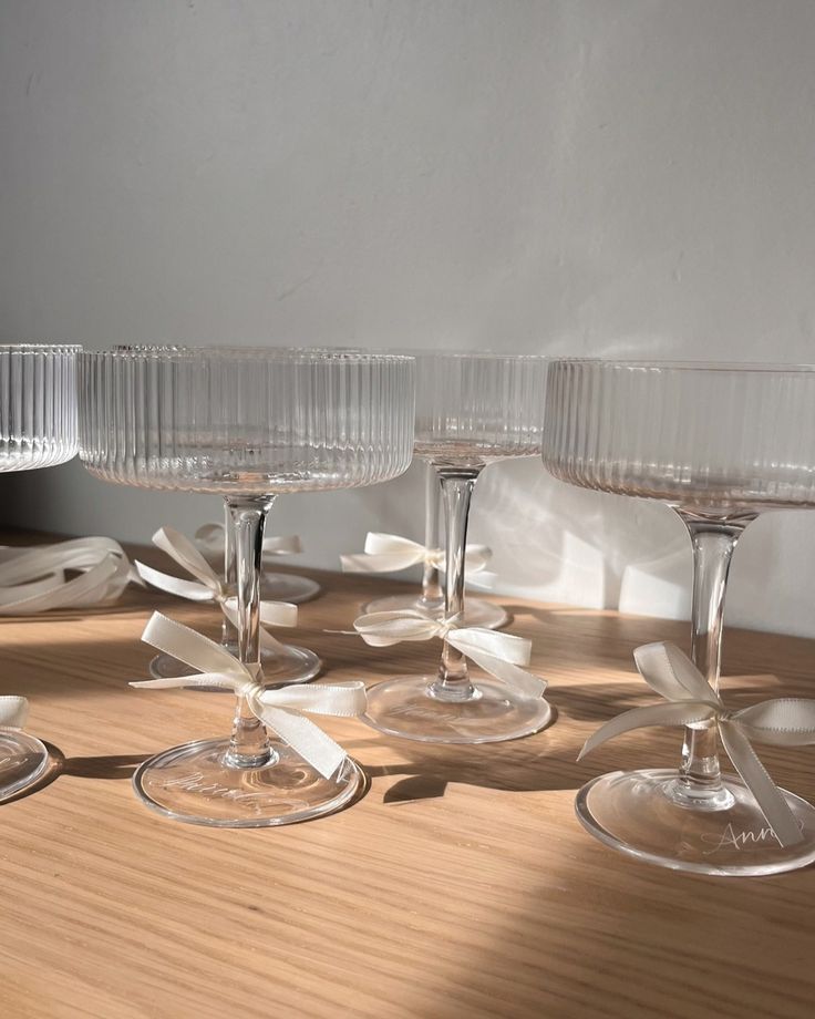 four wine glasses sitting on top of a wooden table next to plates and napkins