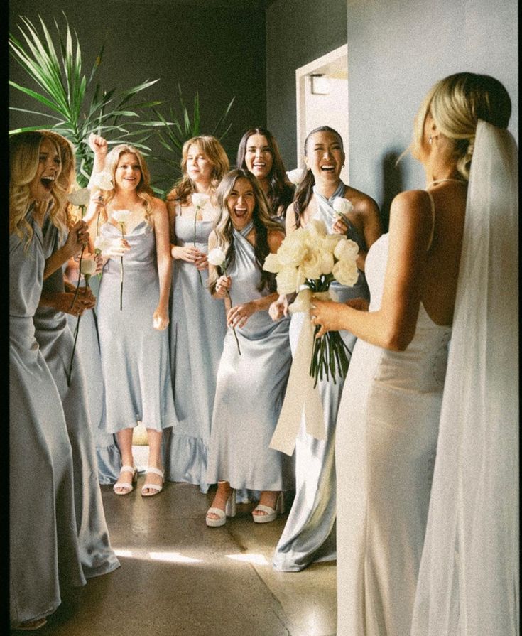 a group of women standing next to each other in front of a wall holding flowers