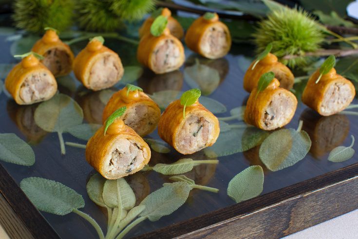 some food that is sitting on top of a black tray with green leaves around it