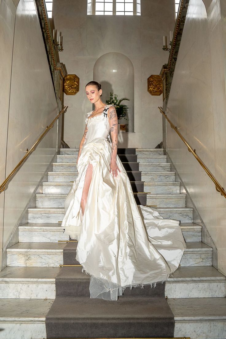 a woman in a white dress walking down some stairs