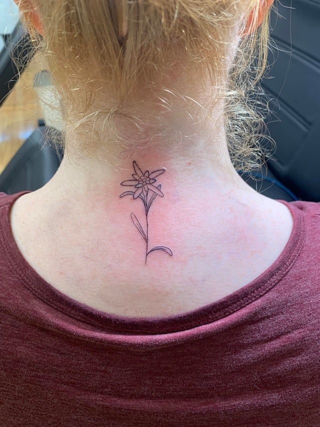 a woman with a small flower tattoo on her neck and behind her head is a red shirt