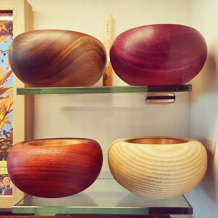 three wooden bowls sitting on top of glass shelves