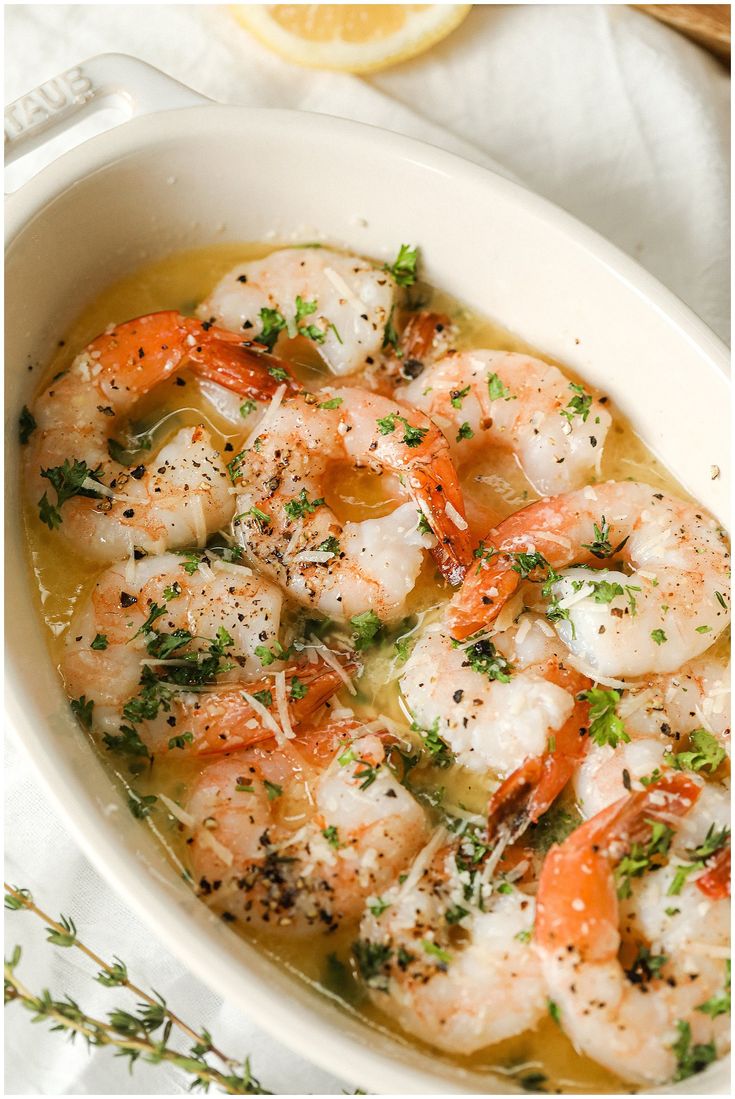 a white bowl filled with shrimp and carrots on top of a table next to a lemon wedge