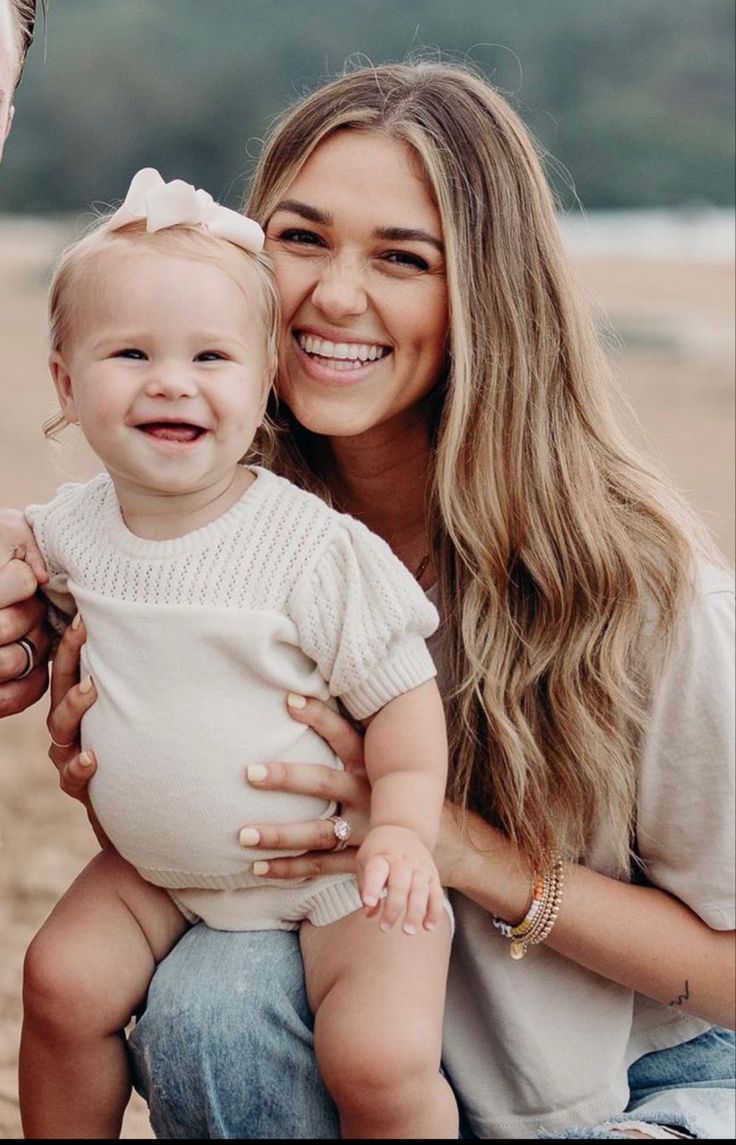 a woman holding a baby and smiling at the camera while sitting next to her husband