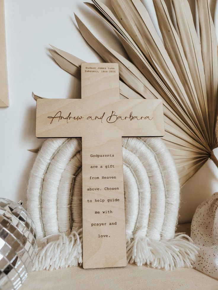 a wooden cross sitting on top of a table next to some feathers and palm leaves