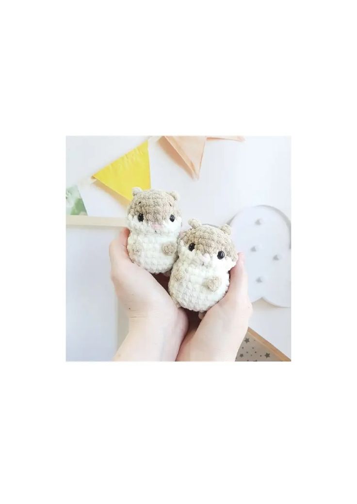 two small crocheted animals are held in someone's hands, one is brown and the other is white