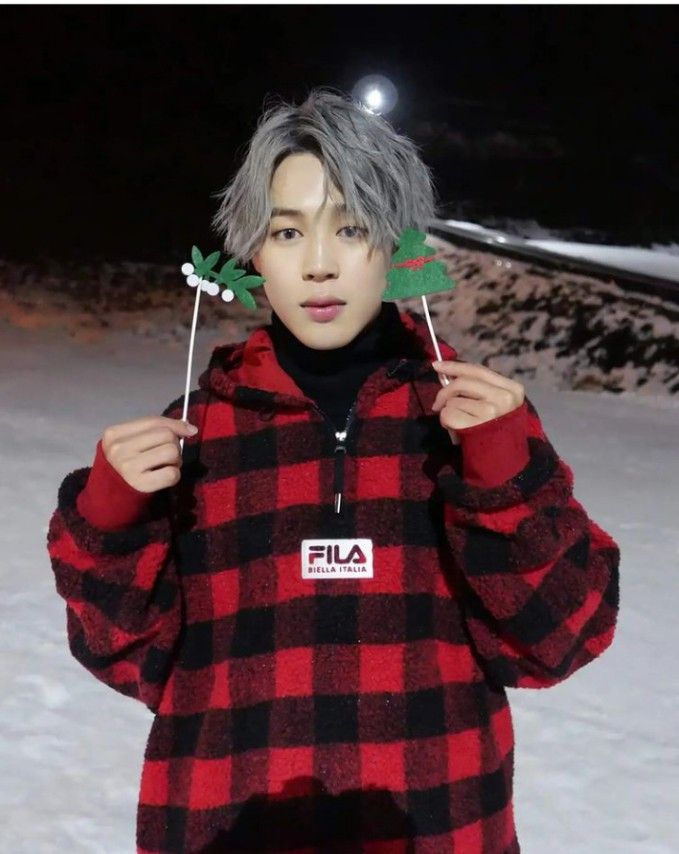 a person standing in the snow holding up two fake leaves on their head and wearing a flannel jacket