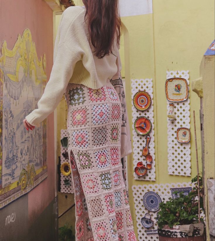 a woman standing in front of a wall covered with pictures and magnets on it