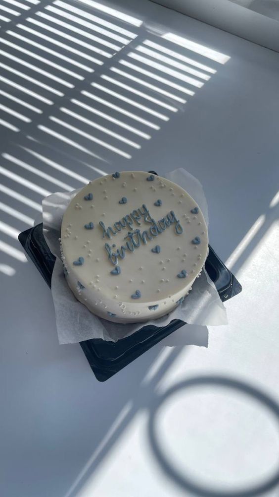 a birthday cake sitting on top of a table next to a pair of blue scissors