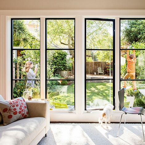 a living room filled with furniture and lots of windows covered in glass doors that look out onto the backyard