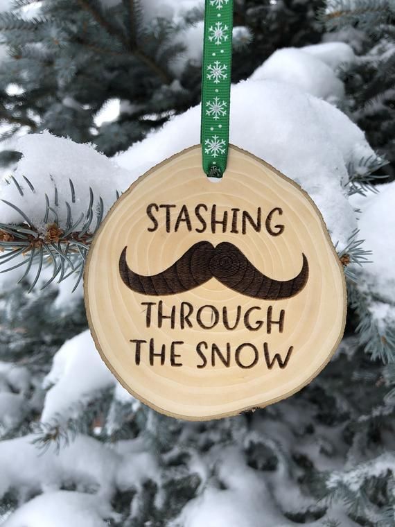 a wooden ornament hanging from a tree with snow on it's branches