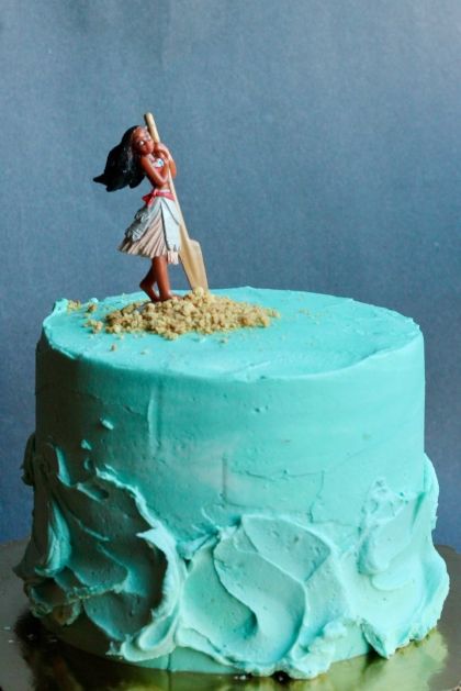 a cake with blue frosting and a small figurine on top that looks like a girl holding a baseball bat