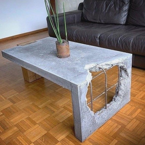 a table made out of concrete with a potted plant on it and a couch in the background