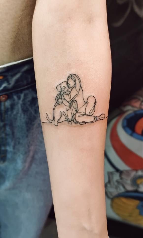 a woman's arm with a small tattoo of two dogs sitting on top of each other