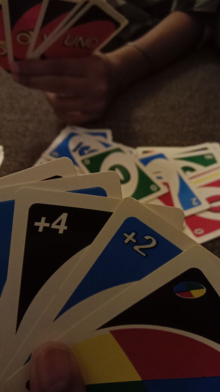 a person holding several cards with numbers on them in front of a table full of other playing cards