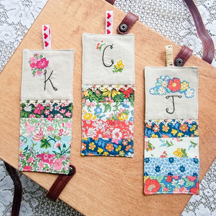 three pieces of fabric with flowers on them sitting on top of a wooden cutting board