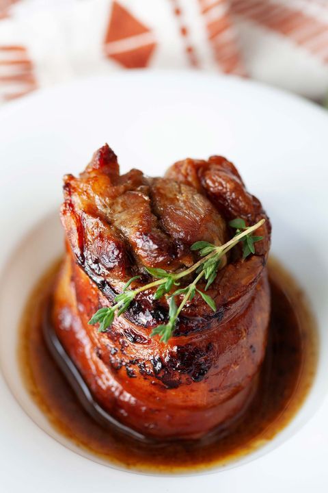 a white plate topped with meat covered in sauce and garnished with green herbs