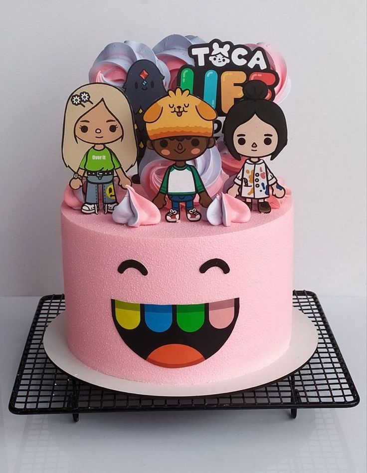 a pink cake with cartoon characters on top and an emojle decoration around it