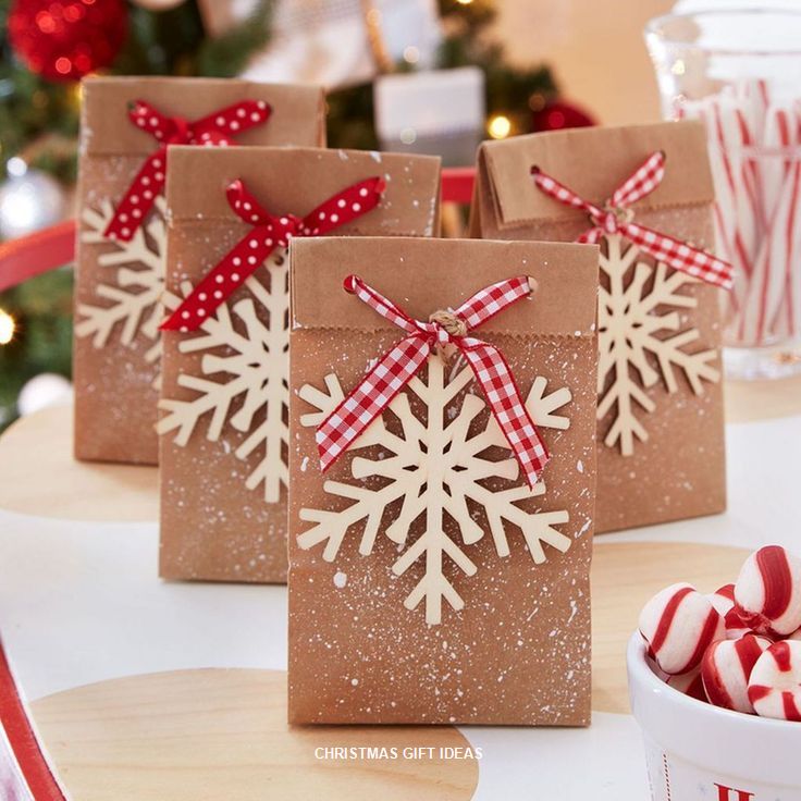 three brown bags with snowflakes on them sitting on a table next to candy canes