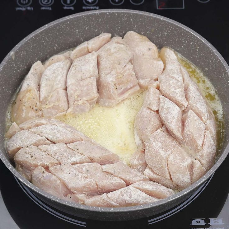 chicken cooking in a pan on top of an electric stove with oil and seasoning