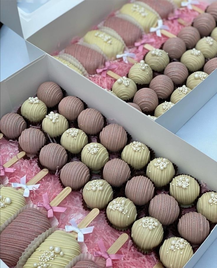 two boxes filled with cake pops covered in frosting