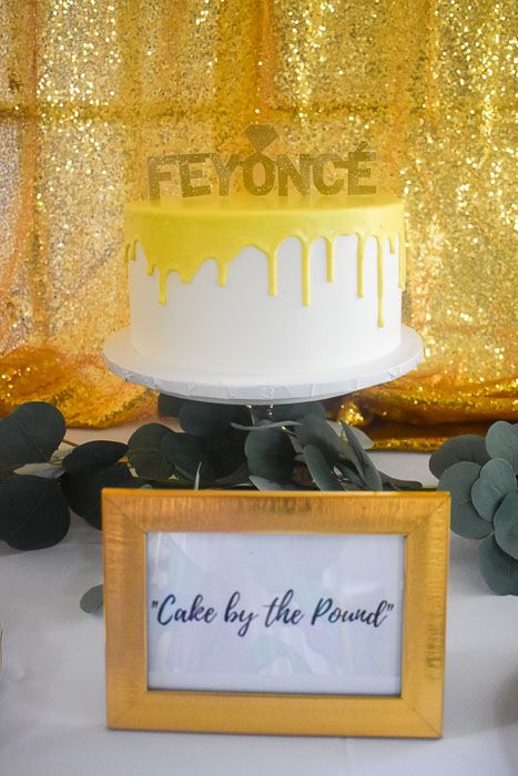 a white and yellow cake sitting on top of a table next to a framed sign