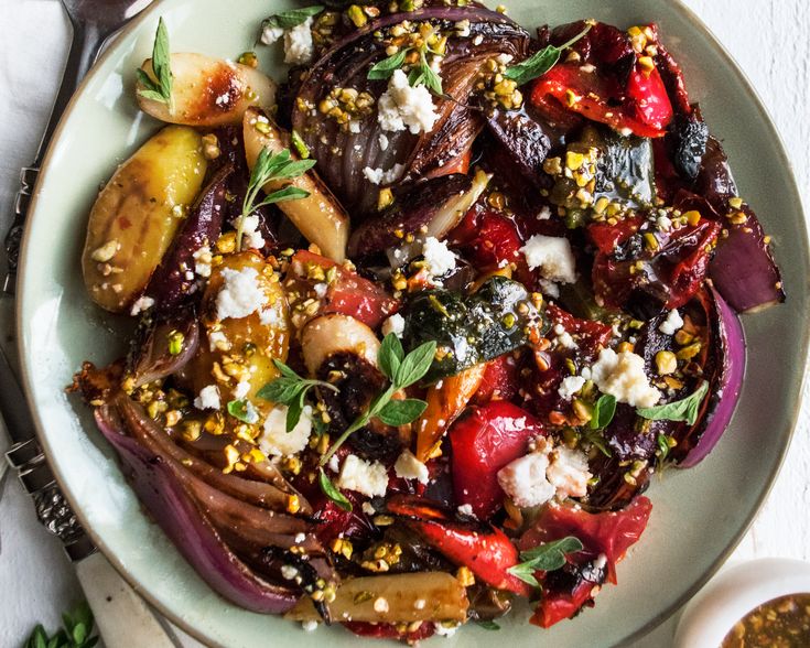 a white plate topped with lots of vegetables and feta cheese on top of it