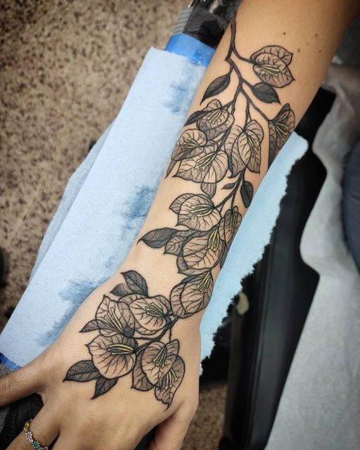 a woman's arm with flowers and leaves on it