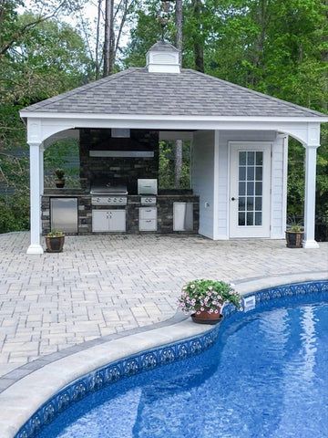 an outdoor kitchen next to a swimming pool