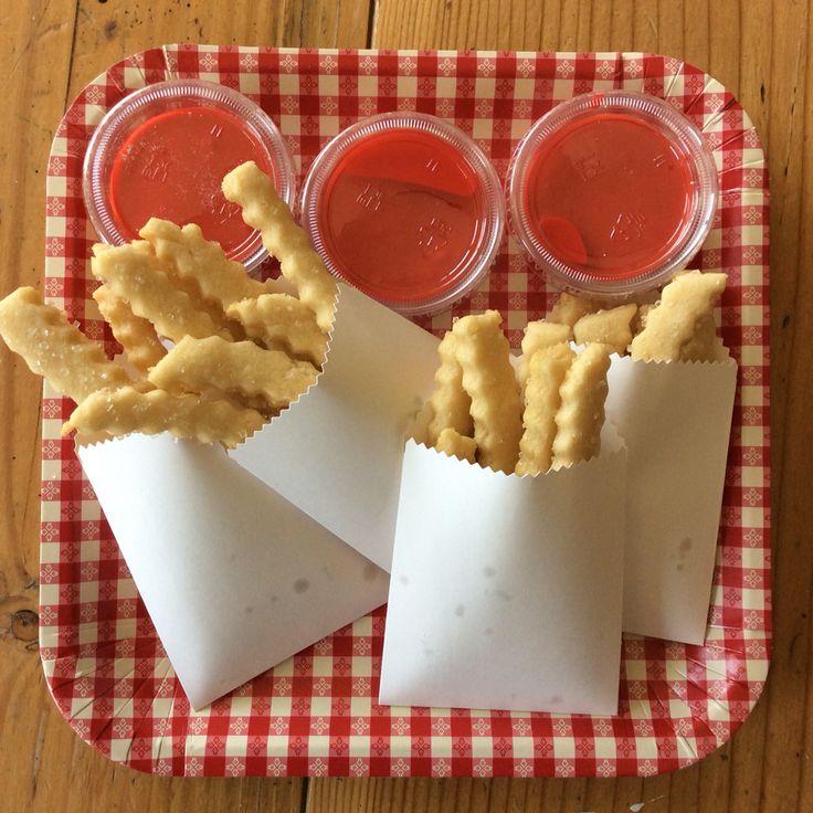 some kind of appetizer on a red and white checkered plate with dipping sauces