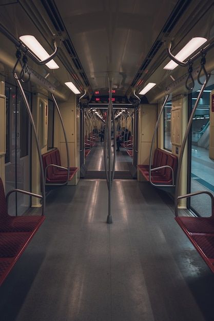 the inside of a subway car with red seats and lights on each side of the doors