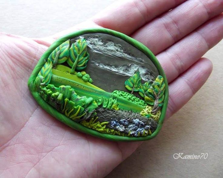 a hand holding a green ring with trees and bushes on it